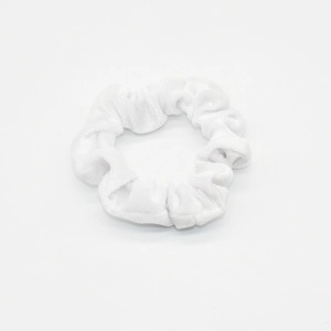 Detail view of a white velvet scrunchie showing soft fabric texture and elastic pleats