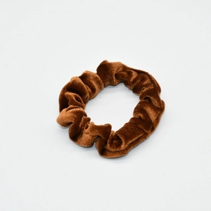 Detailed view of the soft velvet texture and pleats on a brown elastic scrunchie