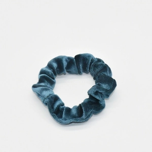 Detail of dark green ribbed velvet scrunchie showing fine texture and premium fabric