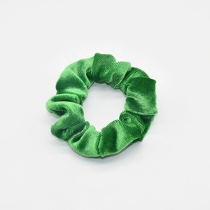 Detailed view of the soft velvet texture and pleats of the green elastic hair scrunchie