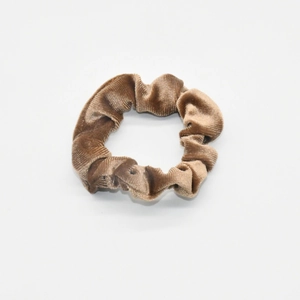 Close-up of velvet scrunchie texture in brown fabric with soft pleats on white background