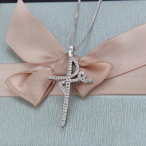 Macro detail of silver cross pendant with crystals on pink ribbon gift background