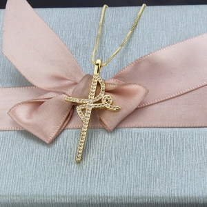 Close-up of golden ballet dancer pendant with tiny stones in a gray gift box