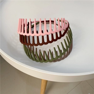 Toothed plastic headbands in pink, brown, and olive green on a white surface