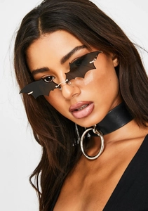 Close-up of bat-shaped sunglasses and black leather choker for gothic street style