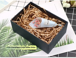 Champagne gold glitter raffia shredded paper filler inside a textured blue gift box