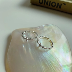 Close-up of 925 sterling silver cross rings with zircon stones on pearl shell