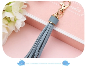 Close-up of Morandi blue PU leather tassel keychain with gold lobster clasp on gift box