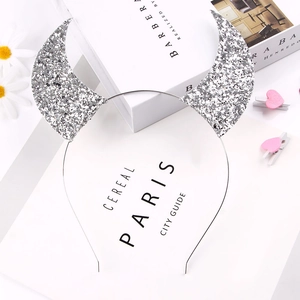 Close-up of a silver sequined devil horn headband on a minimalist white background