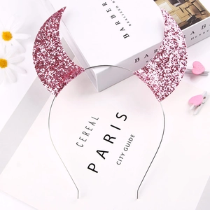 Detail of pink sequin devil horn headband styled with elegant decorative props