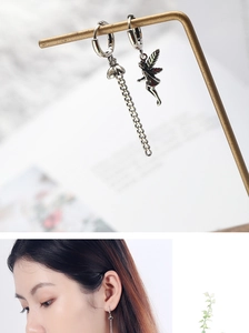 Detail view of gothic style silver earrings featuring chain and fairy pendant on model