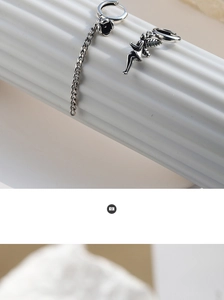 Detail view of vintage oxidized silver asymmetric earrings with angel and chain motifs