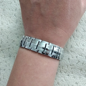 Close-up of titanium magnetic health bracelet in silver links on a wrist with natural light