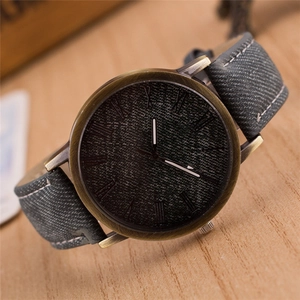Dettaglio dell'orologio vintage in bronzo con cinturino in denim grigio su legno