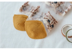 Macro shot of sheer mesh socks featuring cute brown cat patterns and ginger yellow knit heels