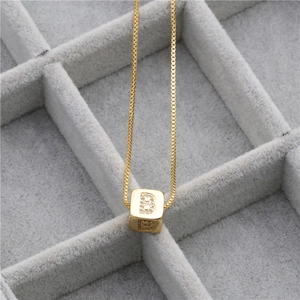 Polished gold micro-pave zircon cube necklace with letter B pendant on grey velvet