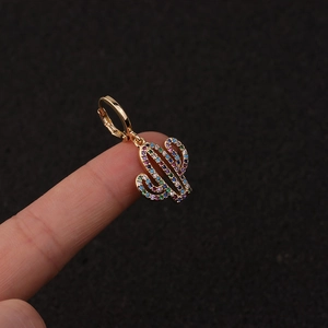 Macro shot of a gold cactus hoop earring with colorful zircon pavé held on a finger