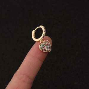 Macro shot of gold heart dangle earring with colorful zircon studs on finger