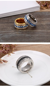 Detailed view of wide pave band rings in gold and silver finish with blue and black crystals