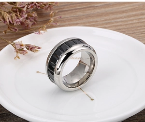 Close-up of wide stainless steel ring with black faceted geometric inlay on tray