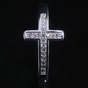 Macro shot of silver cross ring with pavé-set zircons on a high-contrast black background