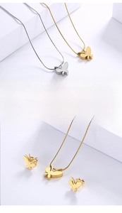 Detailed view of butterfly pendant and earrings in polished gold and silver finish