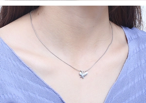 Close-up of a silver butterfly pendant necklace with a sleek snake bone chain style