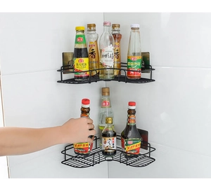 Detail showing hand reaching for a black metal corner shelf with mesh design on tiles