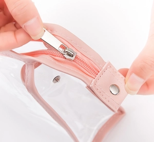 Close-up of pink trim detail and smooth silver zipper on transparent PVC makeup bag