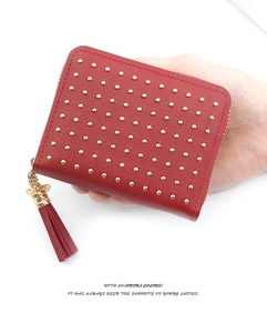 Gros plan du portefeuille court en cuir PU rouge avec rivets dorés et gland en main
