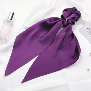 Detail of a purple satin ribbon scrunchie with silk texture on a white backdrop