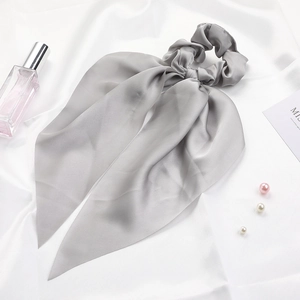 Detail of grey satin bow scrunchie with long ribbons on silk background with pearls