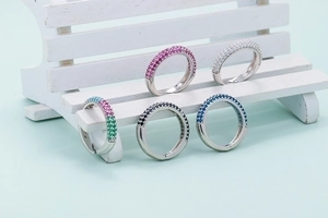 Fashionable micro-pave zircon rings in five vibrant colors displayed on a white bench