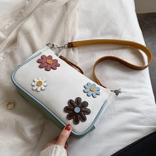 Gros plan du sac fourre-tout en toile crème avec fleurs 3D et bordure bleue