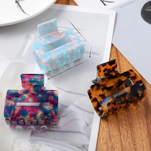 Close-up of square acetate hair claw clips with size markings of 5.5cm by 5cm on magazine