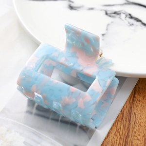 Detailed macro view of the rectangular acetate hair claw with blue and pink floral patterns