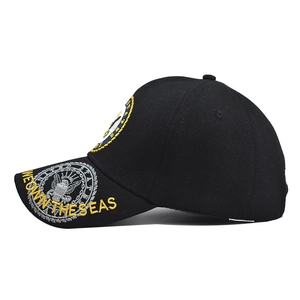 Close-up of yellow 'WE OWN THE SEAS' embroidery and eagle patch on a black tactical cap