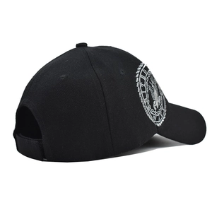 Close-up of black baseball cap with detailed white eagle emblem embroidery and military patches