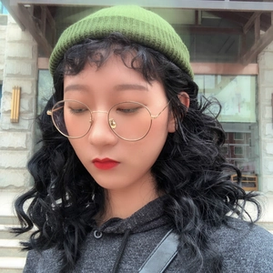 Trendy green knit beanie hat for women with round gold frame glasses in outdoor setting
