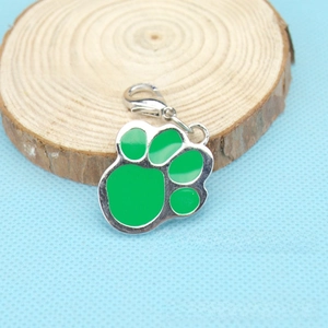 Detail of a green paw print pet tag with silver metal trim and lobster clasp