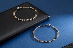 Detail of two-tone gold and silver stainless steel chain bracelets on dark leather background