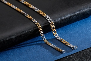 Detail of two-tone gold and silver Cuban chain link bracelet on black leather