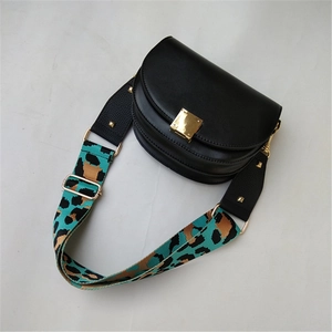 Detail of adjustable leopard print bag strap with gold buckle on black saddle bag