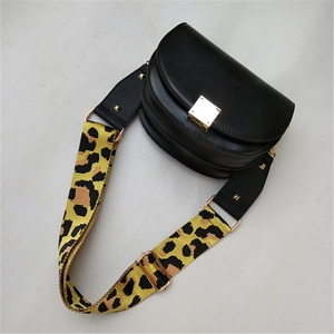 Detail of adjustable leopard print strap on black saddle bag with gold metal buckle