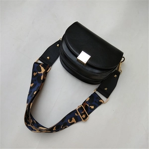 Macro detail of leopard print wide strap with gold buckle on black leather saddle bag