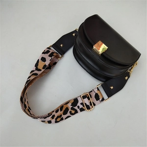 Detail of adjustable leopard print wide strap on a black saddle bag with gold metal buckle