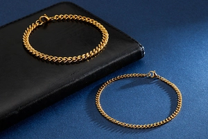 Close-up of two golden stainless steel Cuban link bracelets in different sizes