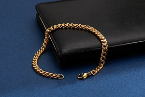 Close-up of golden stainless steel cuban curb chain bracelet with lobster clasp detail
