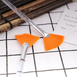 Close-up of fan mask brushes with orange synthetic bristles and transparent acrylic handles