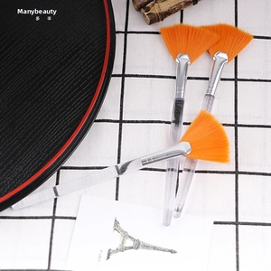 Close-up of three fan-shaped facial mask brushes with orange bristles and clear handles